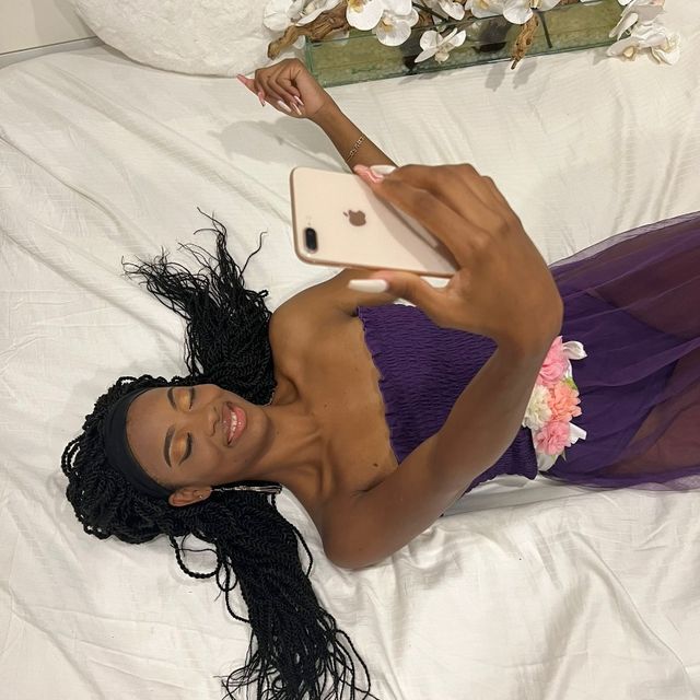 Kvinne ligger på rygg i seng og prater i telefon